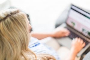 Featured Image for how to start a mom blog showing a woman typing at a computer